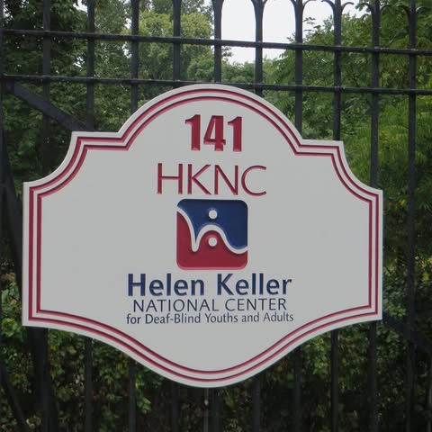 Picture of HKNC Sign that reads HKNC Helen Keller national Center for DeafBlind Youths and Adults with trees in background
